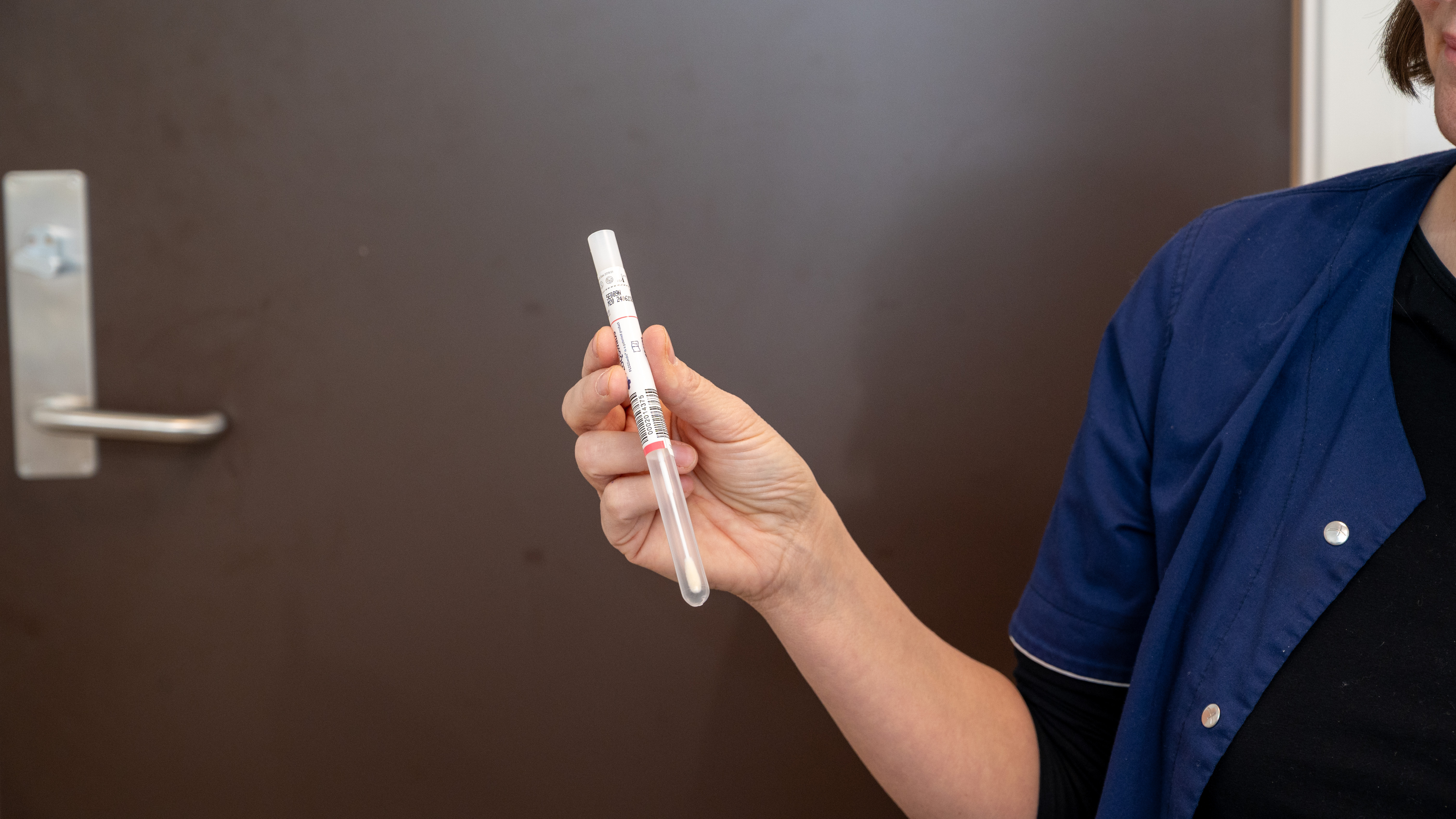 Jordmor holder opp et lite rør. I røret ligger det en Q-tips som er selve testen i HPV-selvtesten.