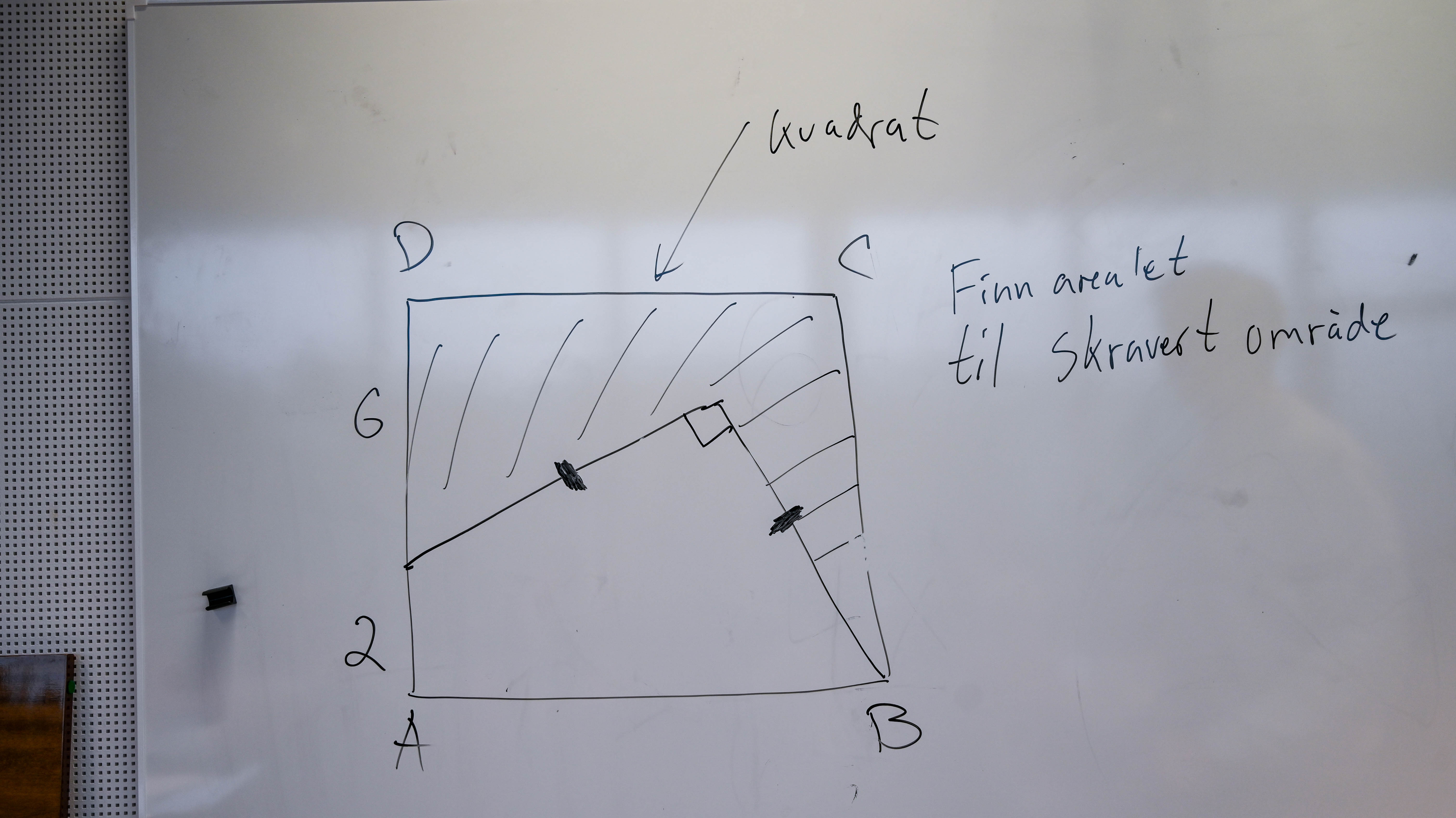 Håndtegnet kvadrat på en hvit tavle med hjørnene A, B, C og D. En skrå linje deler kvadratet i to, og den øvre delen er skravert. Teksten «Finn arealet til skravert område» står til høyre, og «kvadrat» med en pil står over figuren.
