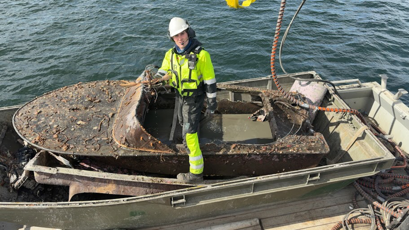 Mann med en levende hummer i et båtvrak. Opprydding i fjorden.